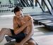 Muscular build man feeling pain in his shoulder after working out at health club.